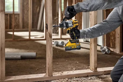 Contractor driving a fastener into a stud wall with a DEWALT 20V XR cordless drill